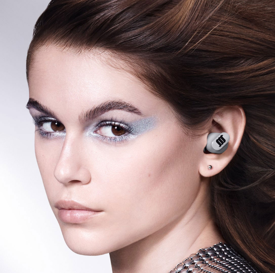 Caucasian female model wearing grey earbuds.