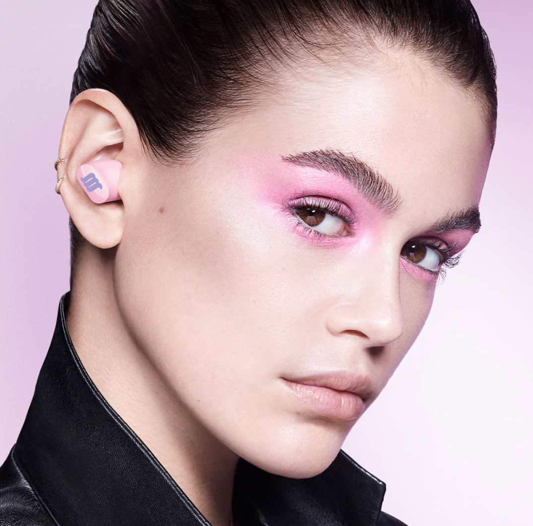 Caucasian female model wearing pink earbuds. 
